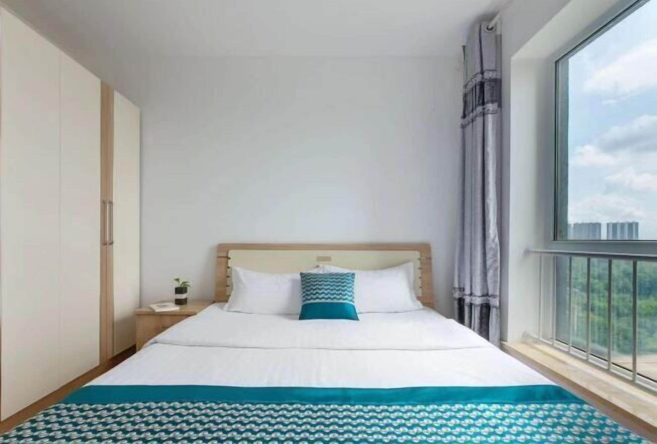 A bedroom with a bed, a nightstand, a window with a view, and a wardrobe.