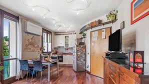 A modern kitchen with white cabinets, a dining area with a table and chairs, and a large window. - Angera Relax & Pool - Lake Maggiore Retreat (Angera)