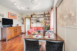 A dining area with a wooden table set for four, a red leather sofa, a bookshelf, and a map on the wall. - Angera Relax & Pool (Angera)