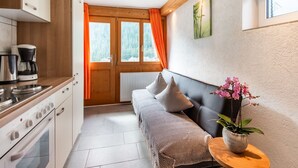 A compact kitchen with modern appliances, a wooden bench with cushions, and a potted orchid. - Apartment in Sankt Gallenkirch Near Ski Slopes (Sankt Gallenkirch)