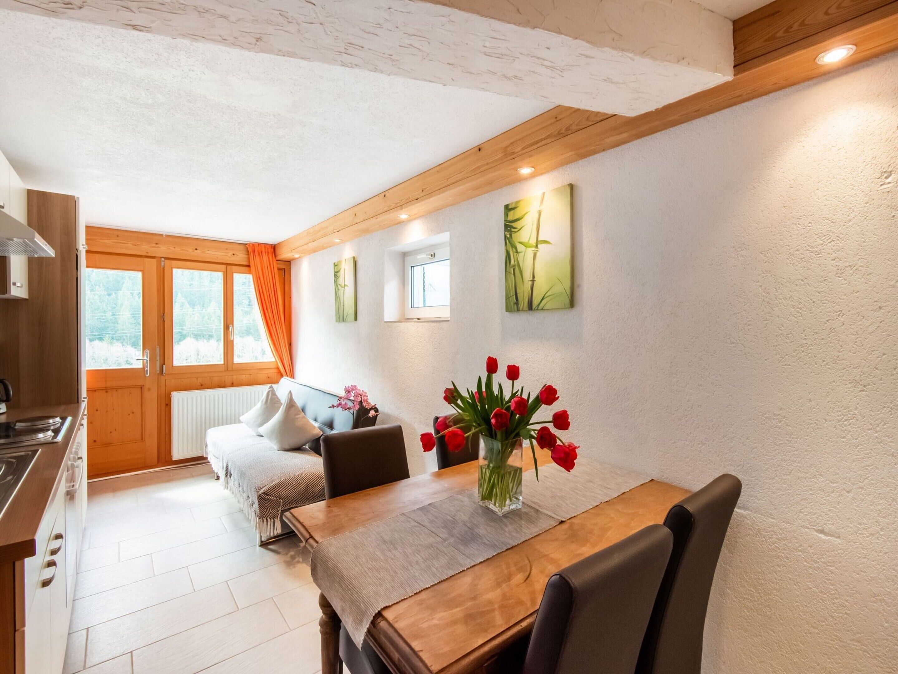 A cozy room with a wooden dining table, a sofa, and a kitchen area.