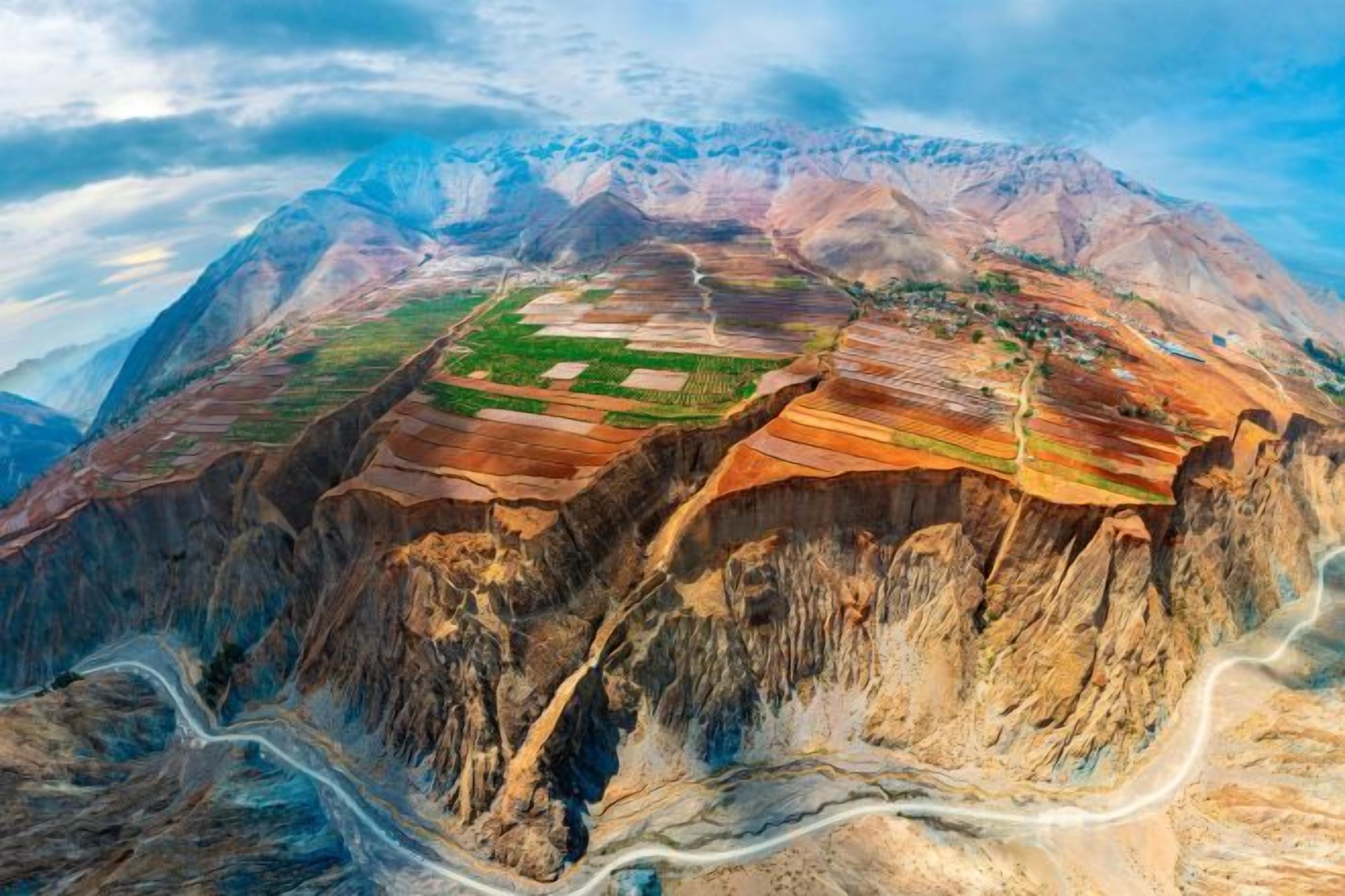 A mountainous landscape with terraced fields and a winding road.