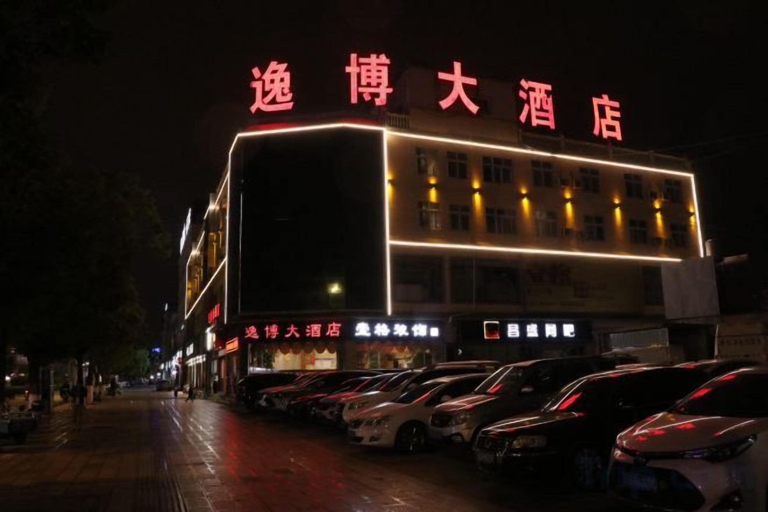 Un hôtel avec une enseigne bien visible, plusieurs étages et un parking rempli de voitures.