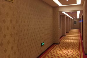 A hotel corridor with patterned walls, a carpeted floor, and a ceiling with recessed lighting. - Huize Yibo Hotel(Huize Ancient City Branch) (Huize)