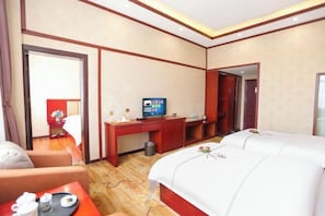 Habitación de hotel con una cama grande, un escritorio con televisor y una mesita con una bandeja de objetos.
