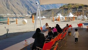 Un resort nel deserto con posti a sedere all'aperto e tende, con montagne sullo sfondo.