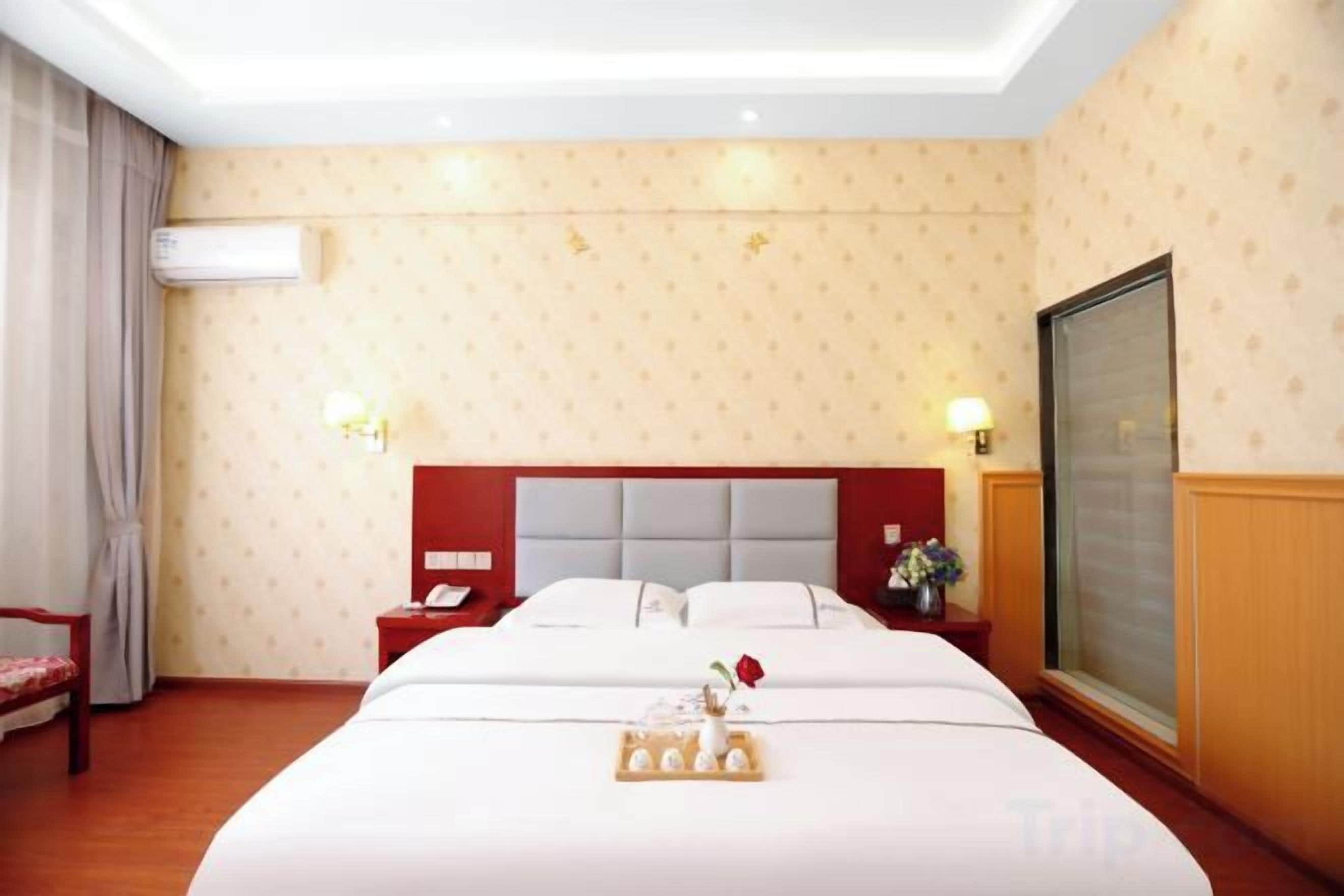 Habitación de hotel con una cama grande, mesitas de noche, una ventana con vistas y un equipo de aire acondicionado.