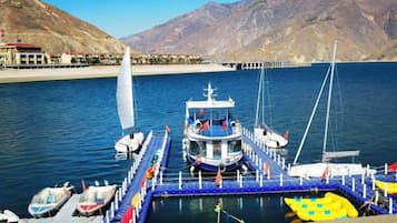 A docked boat with a cabin, moored at a pier with a clear view of the surrounding mountains.