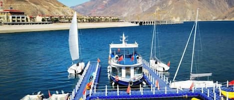 A docked boat with a cabin, moored at a pier with a clear view of the surrounding mountains.