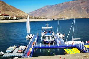 Un barco amarrado con cabina, atracado en un muelle con vistas despejadas de las montañas circundantes.