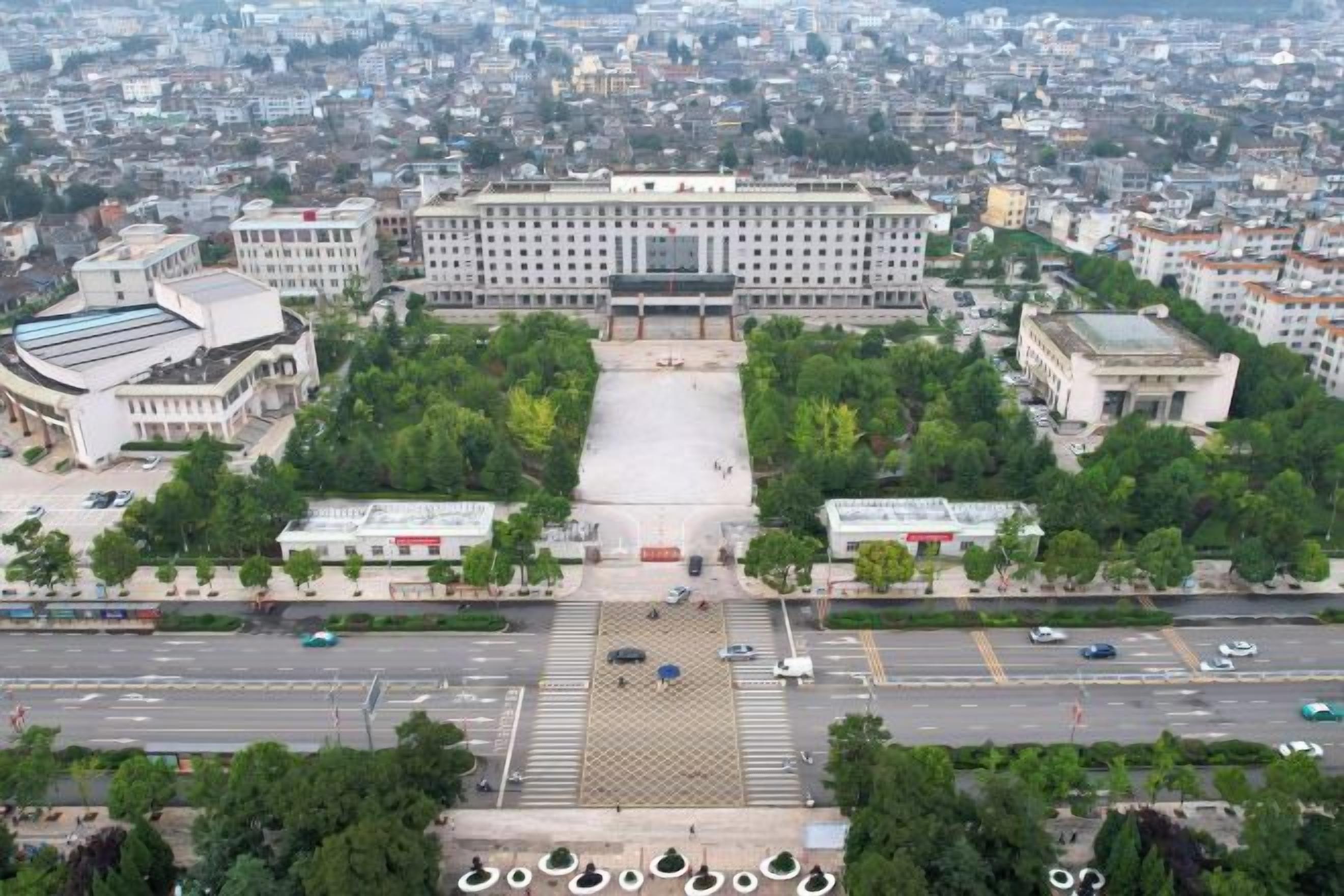 A large building with a central courtyard, surrounded by trees and a parking area.