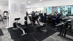 Ein modernes Fitnessstudio mit verschiedenen Trainingsgeräten, darunter Laufbänder, Kraftgeräte und Kurzhanteln.
