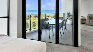 Ein Schlafzimmer mit einer großen SchiebeglasTür, die auf einen Balkon mit Tisch und Stühlen führt, mit Blick auf eine reizvolle Aussicht.