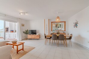 Uma sala de estar moderna com área de refeições, televisão e uma grande janela.