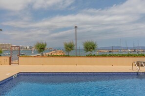 Ein Schwimmbecken mit Blick auf Boote und einen Hafen.
