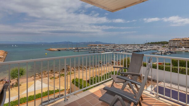 A balcony with a view of a marina, beach, and distant mountains. - Flateli l'Escala Vista Mar (L'Escala)