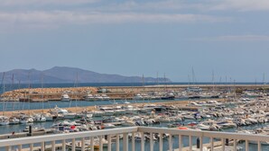 A marina with numerous boats docked, a rocky breakwater, and mountains in the background. - Flateli l'Escala Vista Mar (L'Escala)