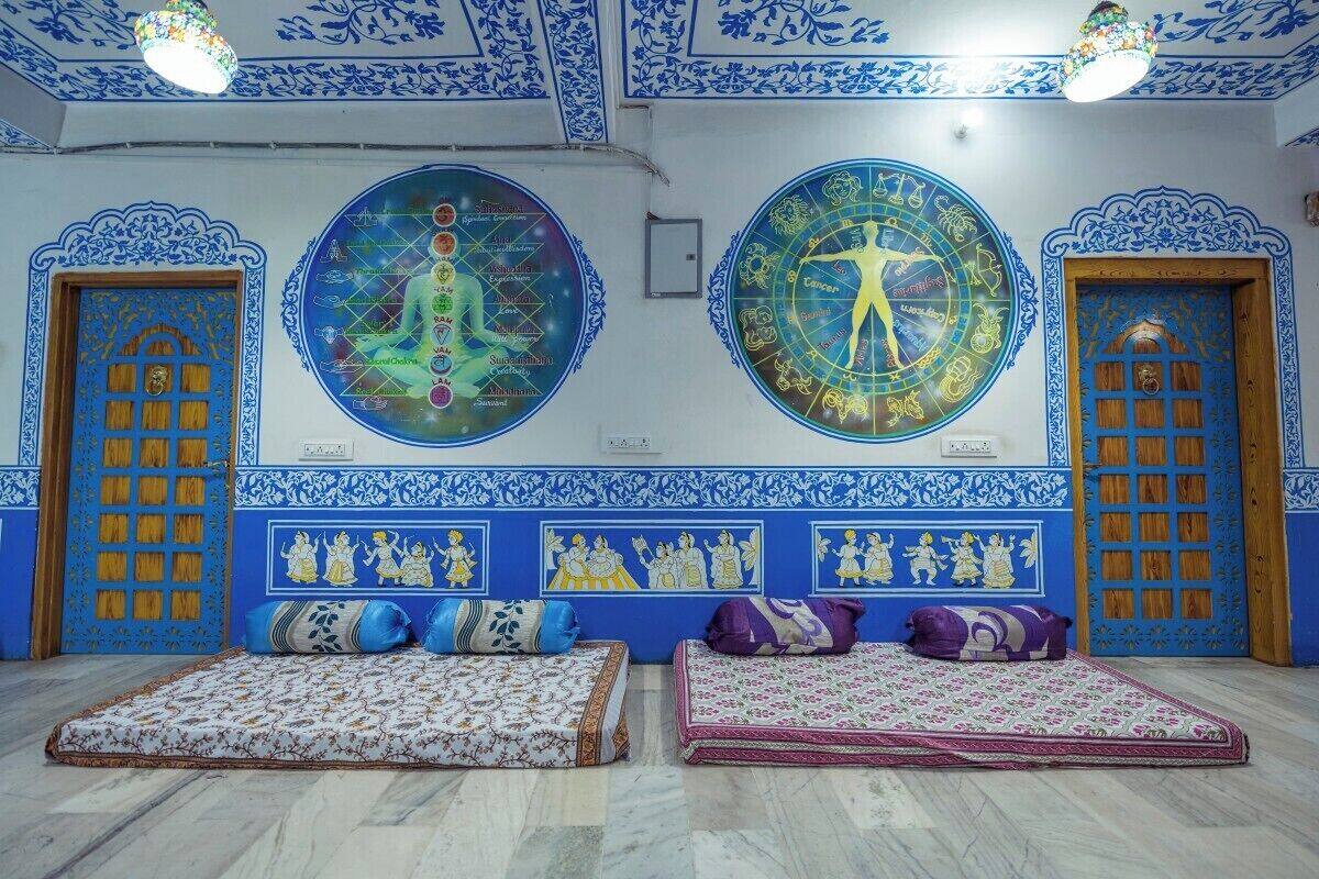 A room with two beds, a wall with zodiac signs, and traditional blue and white decor.