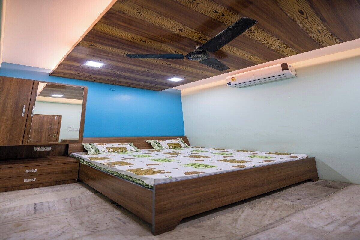 A bedroom with a wooden bed, a ceiling fan, a mirror, and a wall-mounted air conditioner.