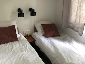 A twin room with two beds, each with a pillow and a bedside table with a lamp. - Peaceful Stay Near the Woods (Zutendaal)