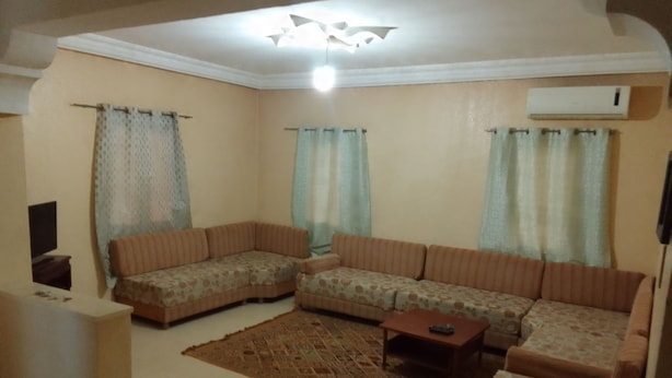 A living room with a sectional sofa, a coffee table, and a patterned rug. - Dar Mourad (Djerba Midun, Médenine)
