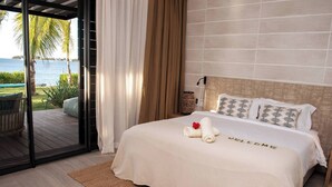 Un dormitorio con cama, vistas al mar y un balcón con mesa y sillas.