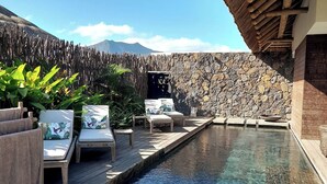 Un área de piscina con sillas de descanso y una pared de piedra.