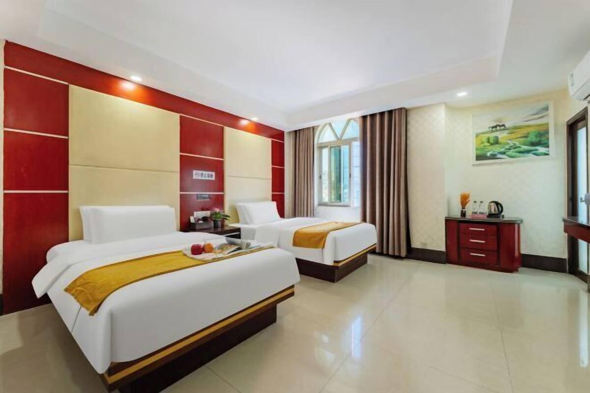Habitación de hotel con dos camas, un escritorio pequeño, un armario y un cuadro en la pared.
