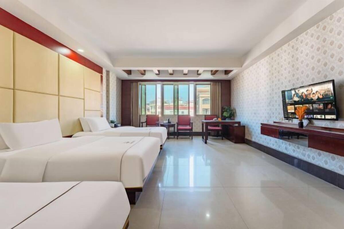Habitación de hotel con dos camas, televisión, escritorio y zona de estar.