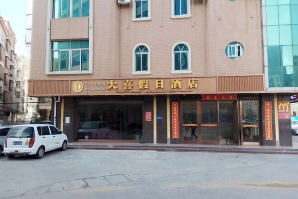 A hotel with a sign reading "DAXI HOLIDAY INN" and a McDonald's logo on the right.