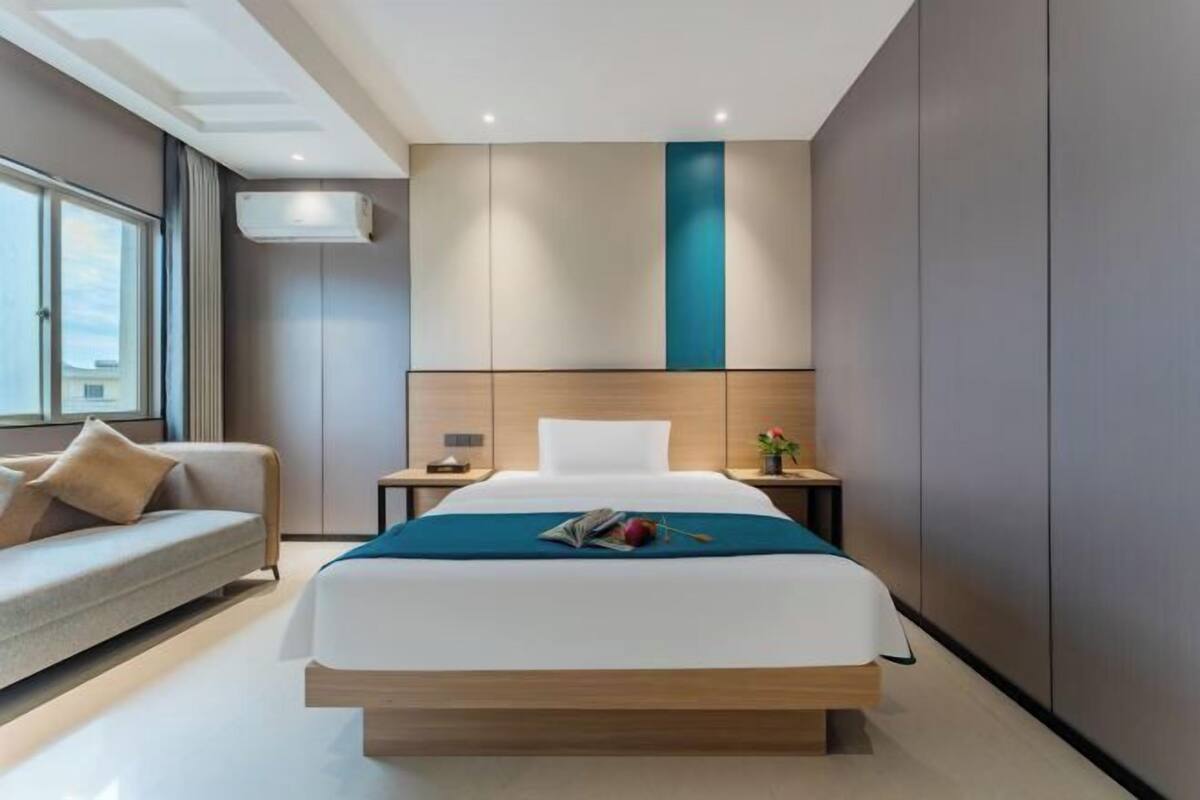 Una habitación de hotel moderna con una cama grande, un sofá, una mesita de noche y una ventana.