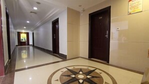 A hotel corridor with a polished floor, a large compass design, and dark wooden doors. - Q+ Maoming Daxi Holiday Hotel (Maoming)