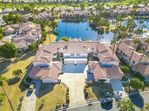 Zona residencial con varias casas, una piscina central y un campo de golf al fondo.