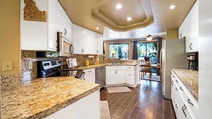 A modern kitchen with granite countertops, white cabinetry, and a central island.