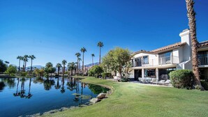 A well-maintained lawn, a pool, and a two-story house with a balcony.