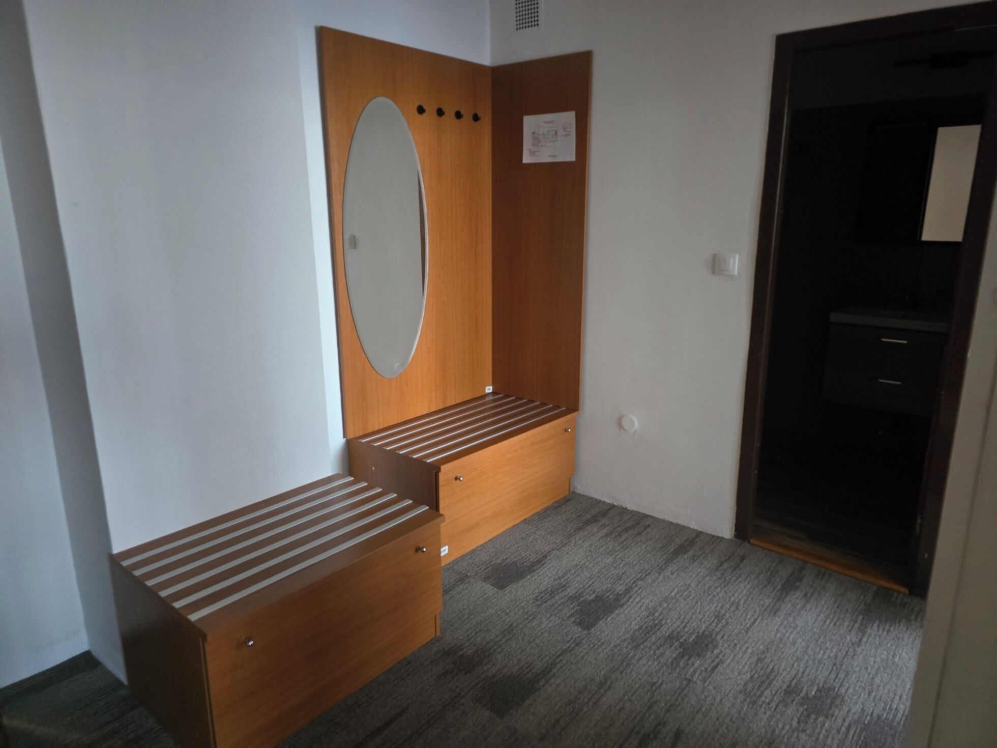 A room with a wooden bench, a mirror, and a wardrobe.