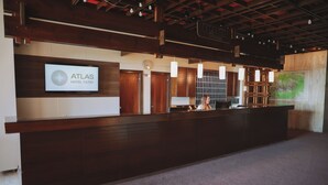 A reception area with a wooden reception desk, a sign for 'Atlas Hotel Tatry', and a large map on the wall. - Atlas Hotel Tatry (Vysoké Tatry)