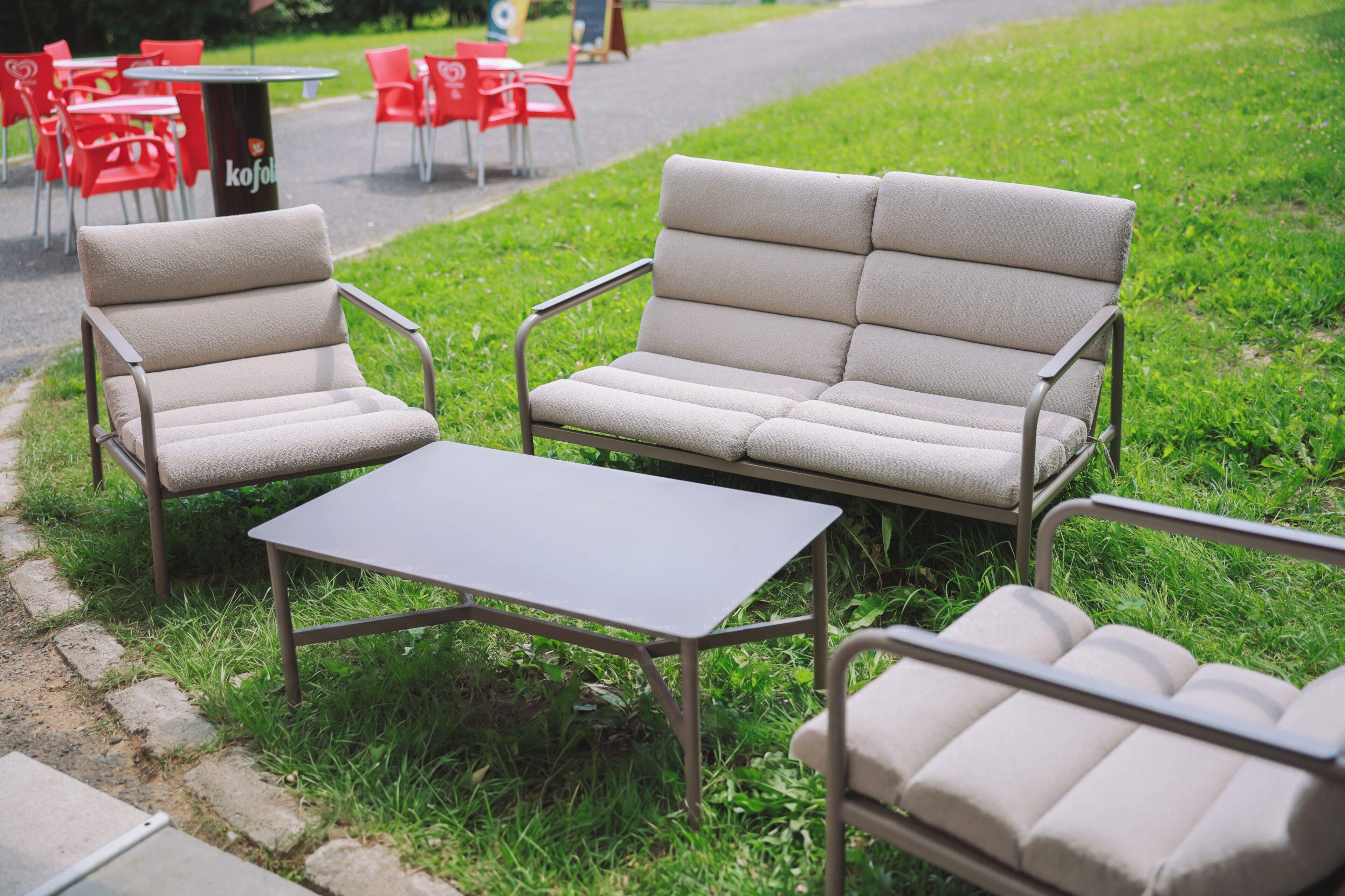 Un espacio al aire libre con un sofá y sillas, una mesa y un cubo de basura.