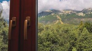 A mountain landscape with a clear sky, a winding path, and dense forest. - Atlas Hotel Tatry (Vysoké Tatry)