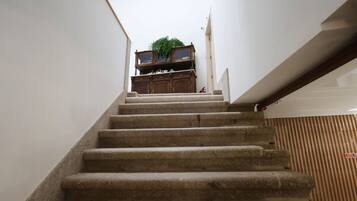 Un escalier en pierre menant à un palier où se trouvent un meuble en bois et une plante.