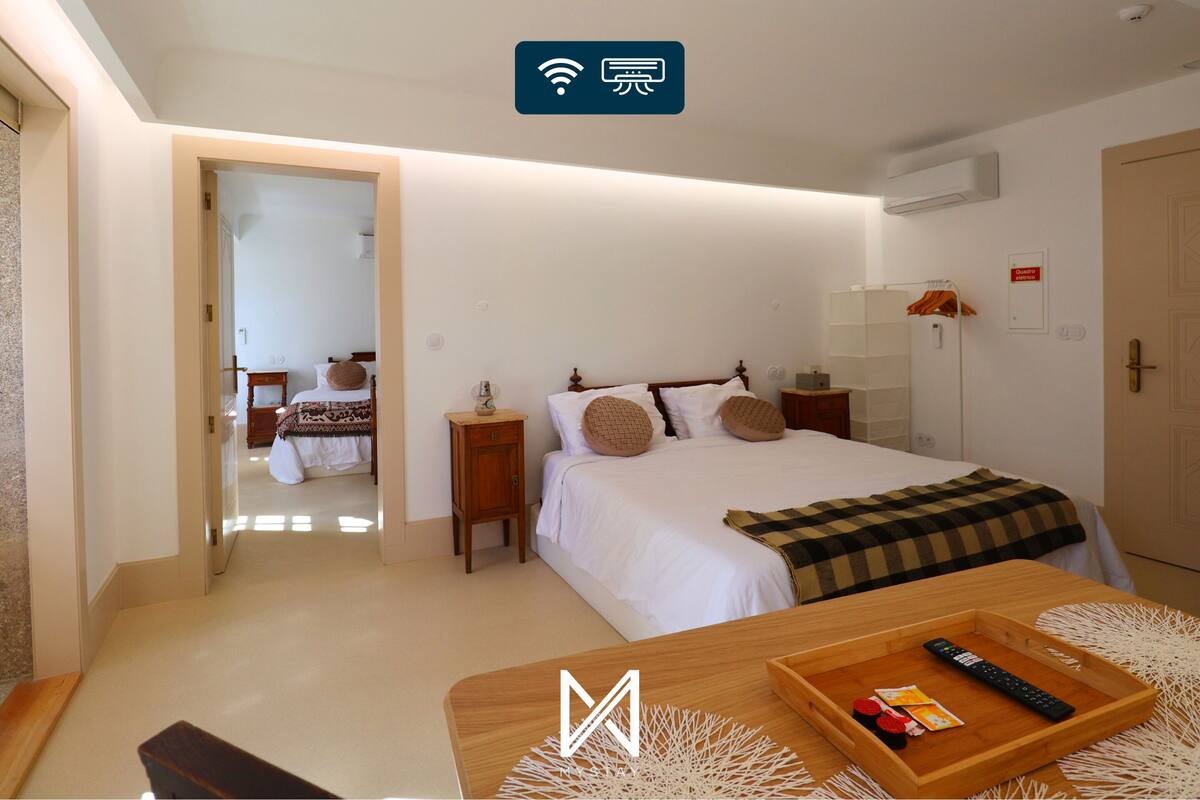 A hotel room with a bed, bedside tables, a desk with a tray, and a wardrobe.