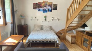 Ein Schlafzimmer mit einem Bett, einem Schreibtisch, einem Stuhl, einer Holztreppe und einer Wand mit drei gerahmten Bildern.
