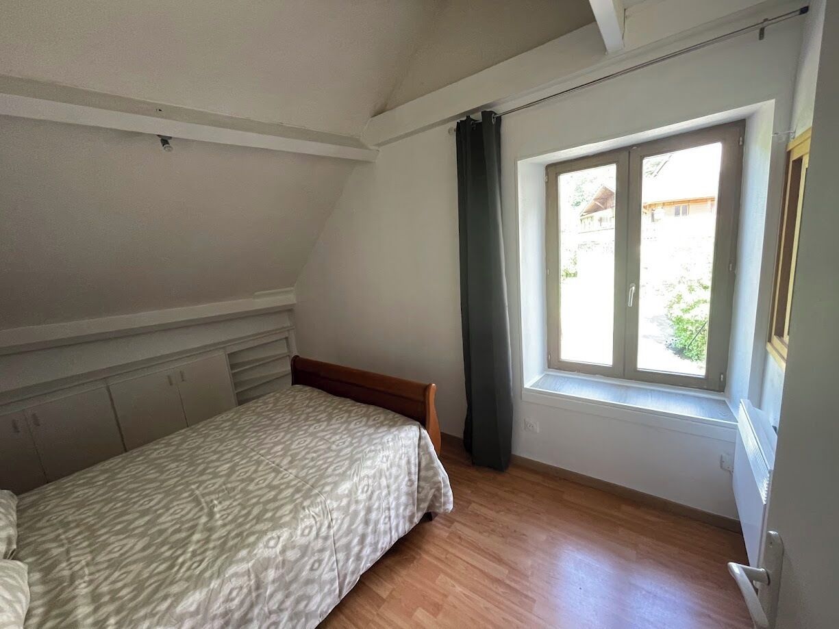 Une chambre à coucher avec un lit, une fenêtre avec des rideaux et un radiateur.