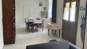 Ein Essbereich mit Tisch und Stühlen, einer Holzkommode und einer Tür mit Kleiderhaken.