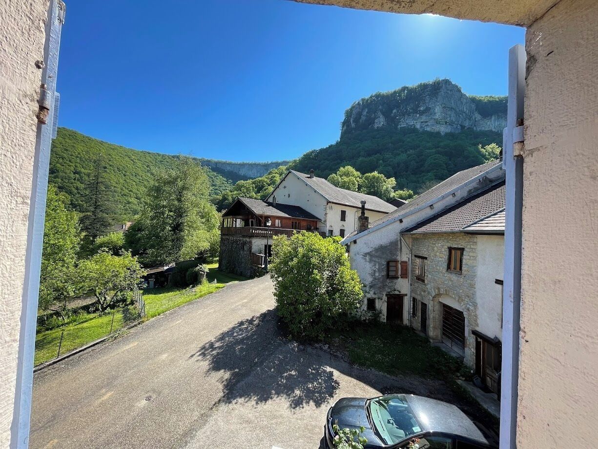 Ein ländliches Dorf mit Steinhäusern, einer Schotterstraße und einem Berg im Hintergrund.