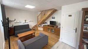 Ein Wohnzimmer mit einer Couch, einem Couchtisch, einem Fernseher, einer Treppe und einem Bücherregal.