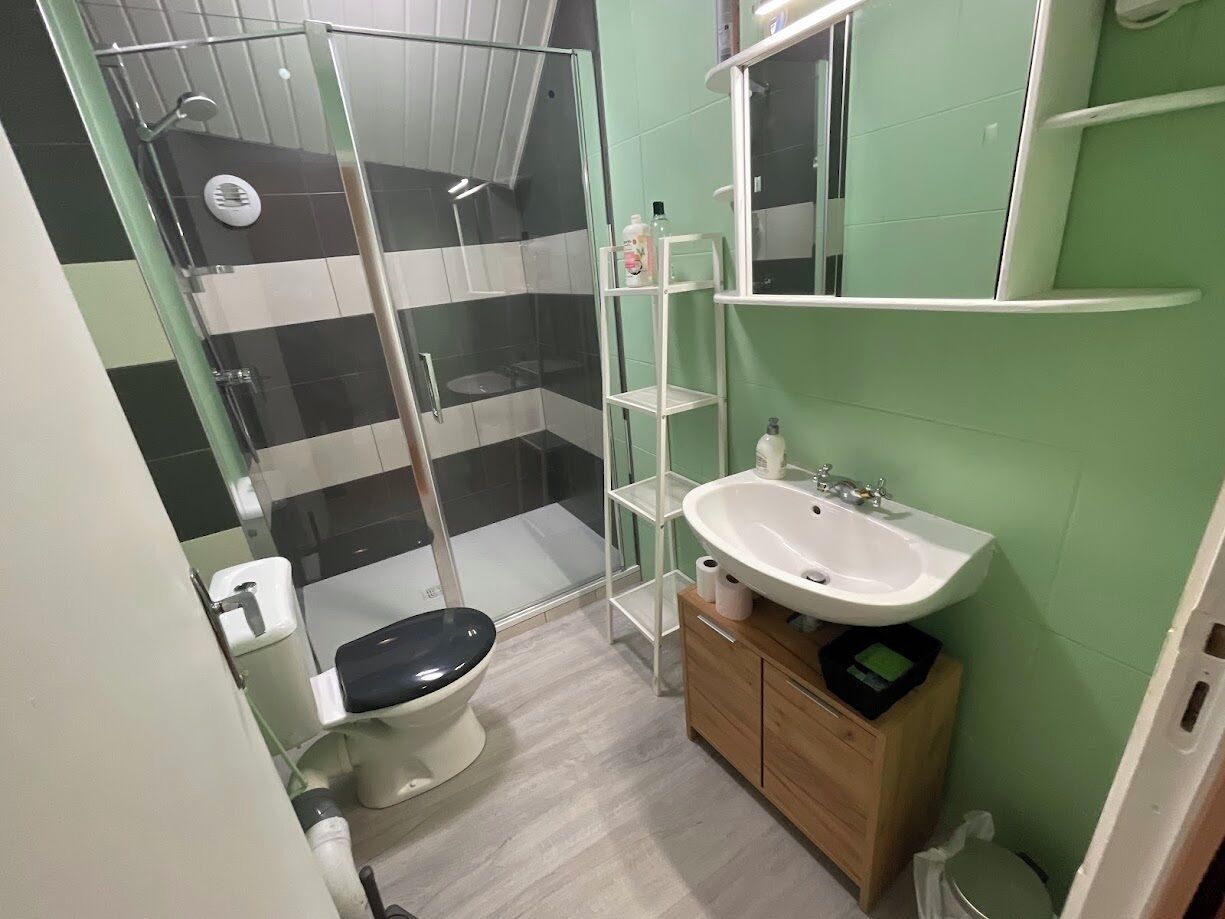 Une salle de bain équipée d’une douche, de toilettes, d’un lavabo et d’un miroir.