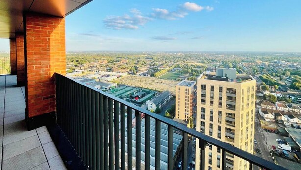 Ein Balkon mit Blick auf eine Stadtlandschaft, darunter Gebäude und ein klarer Himmel.