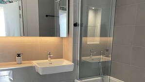 Ein modernes Badezimmer mit einer Duschkabine, einem Waschtisch und einer Toilette.