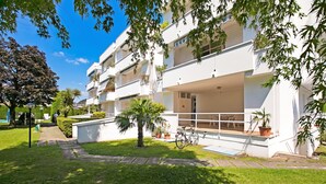 A modern apartment building with balconies, a bicycle, and a well-maintained lawn.